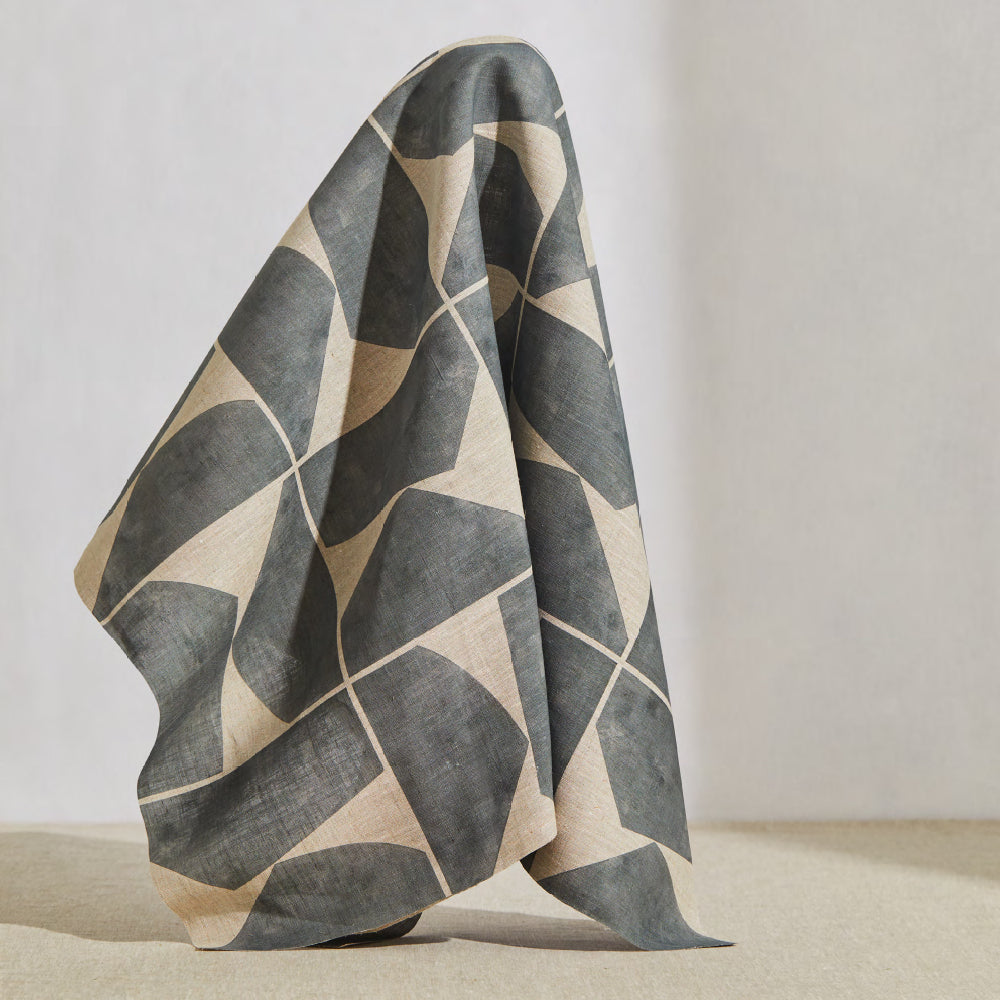 A large piece of draped fabric in a large-scale curvilinear geometric print in gray on a cream field.