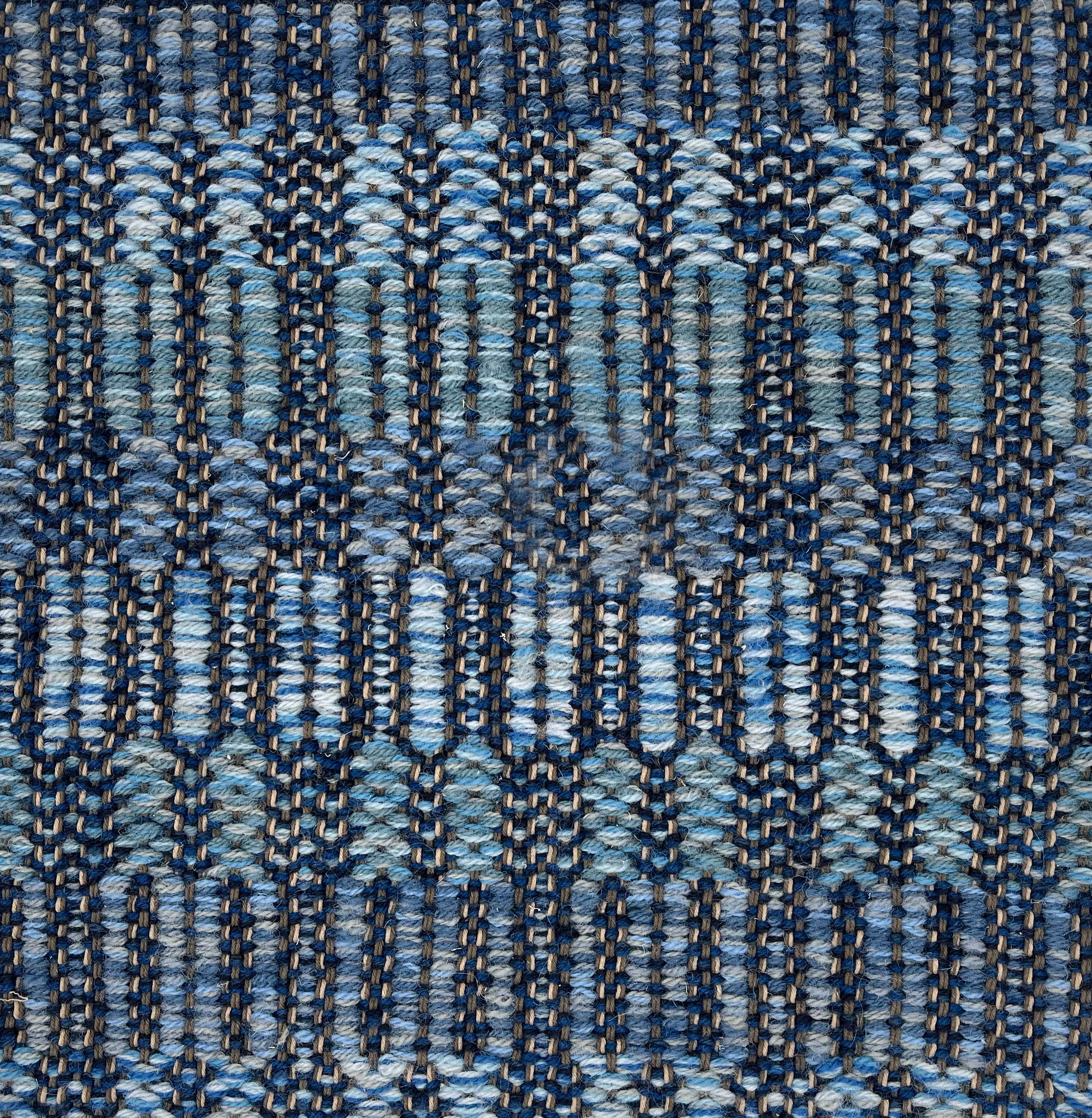 Handwoven rug detail in a geometric  design in blue and black 