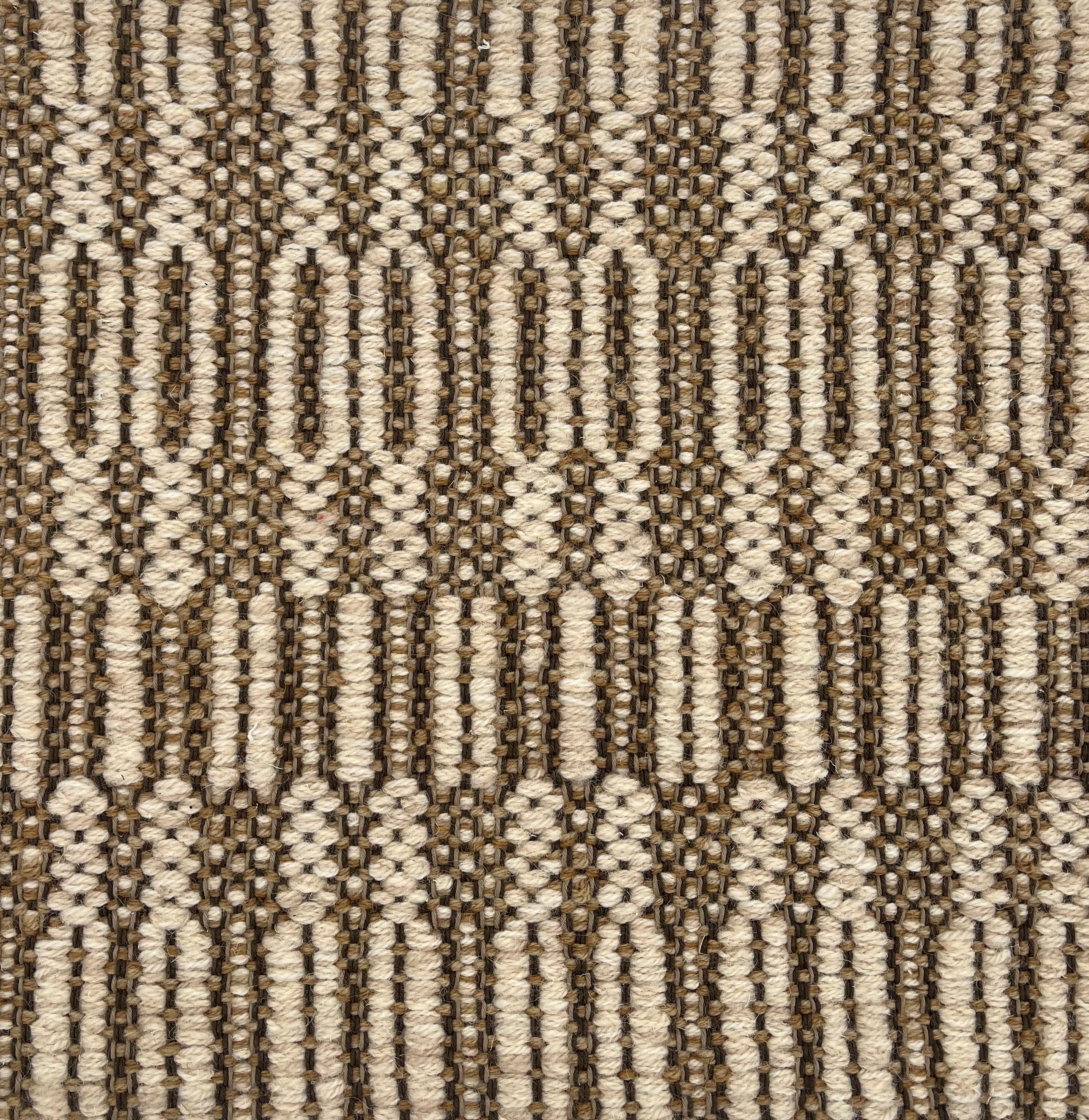 Handwoven rug detail in a geometric   design in tan and beige