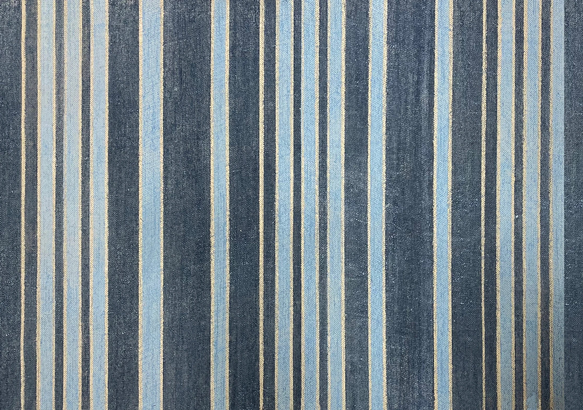 Detail of wallpaper in an irregular stripe print in shades of blue, gold and navy.