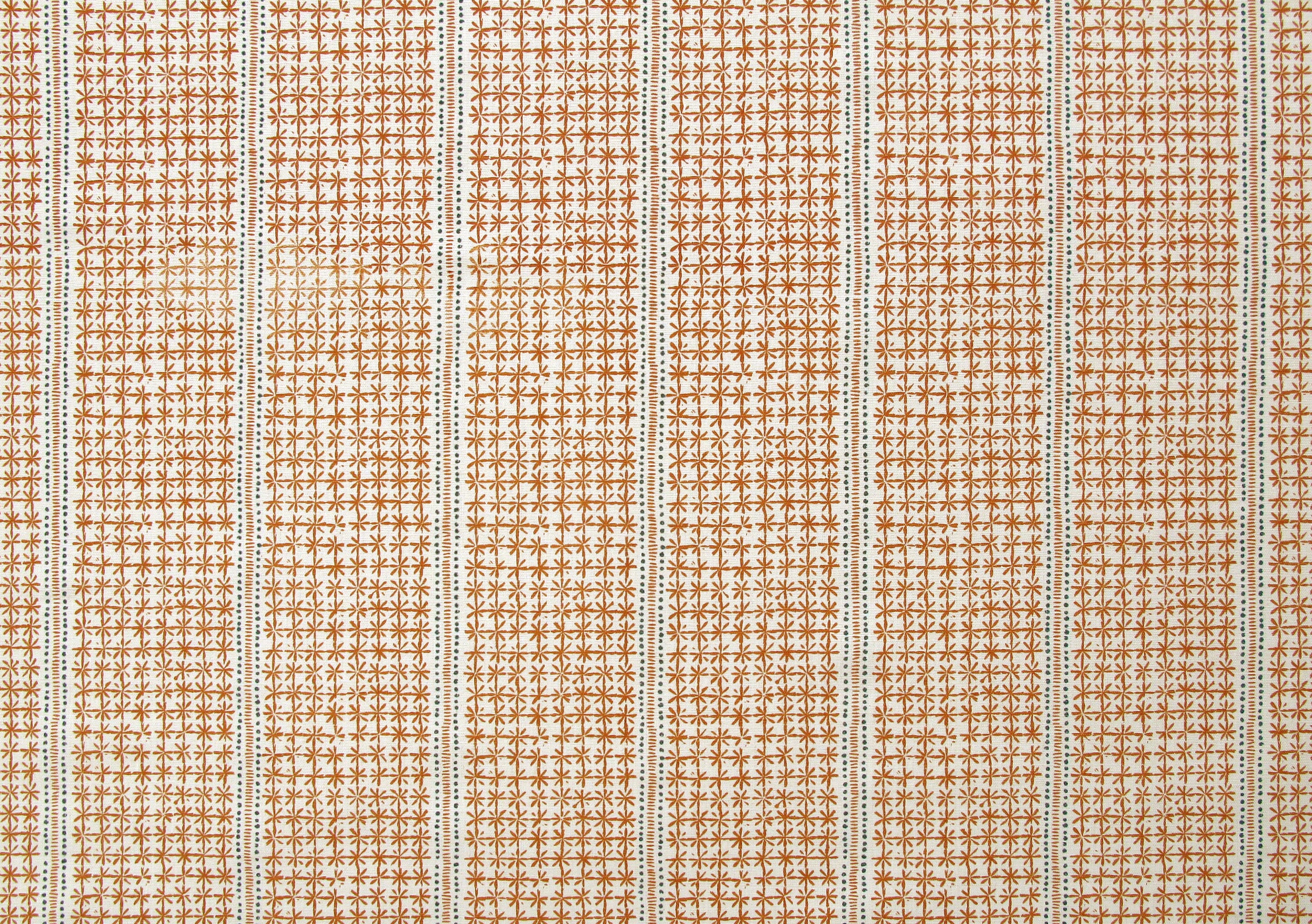 Detail of fabric in a dense repeating stripe and star print in burnt orange on a cream field.