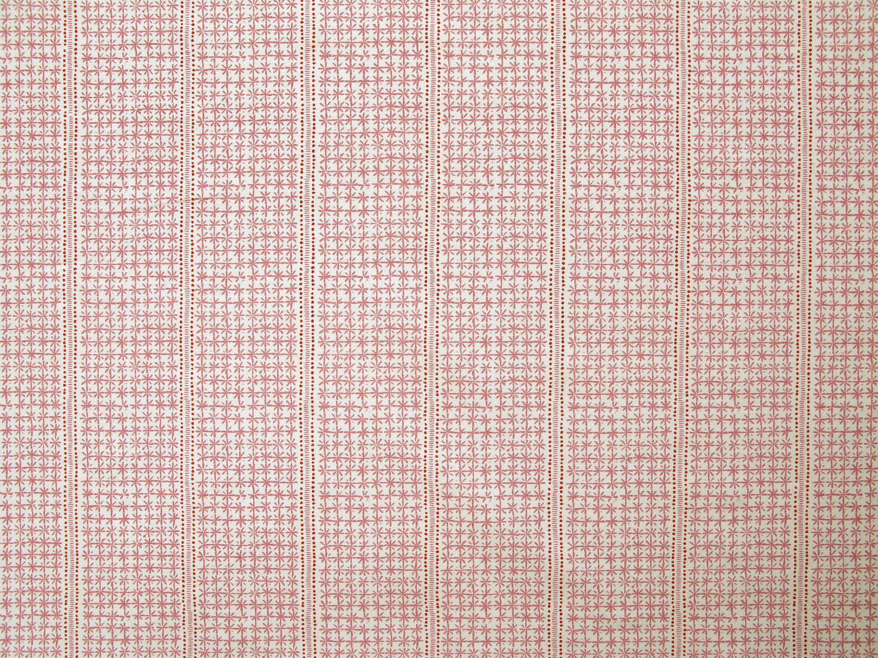 Detail of fabric in a dense repeating stripe and star print in pink on a cream field.