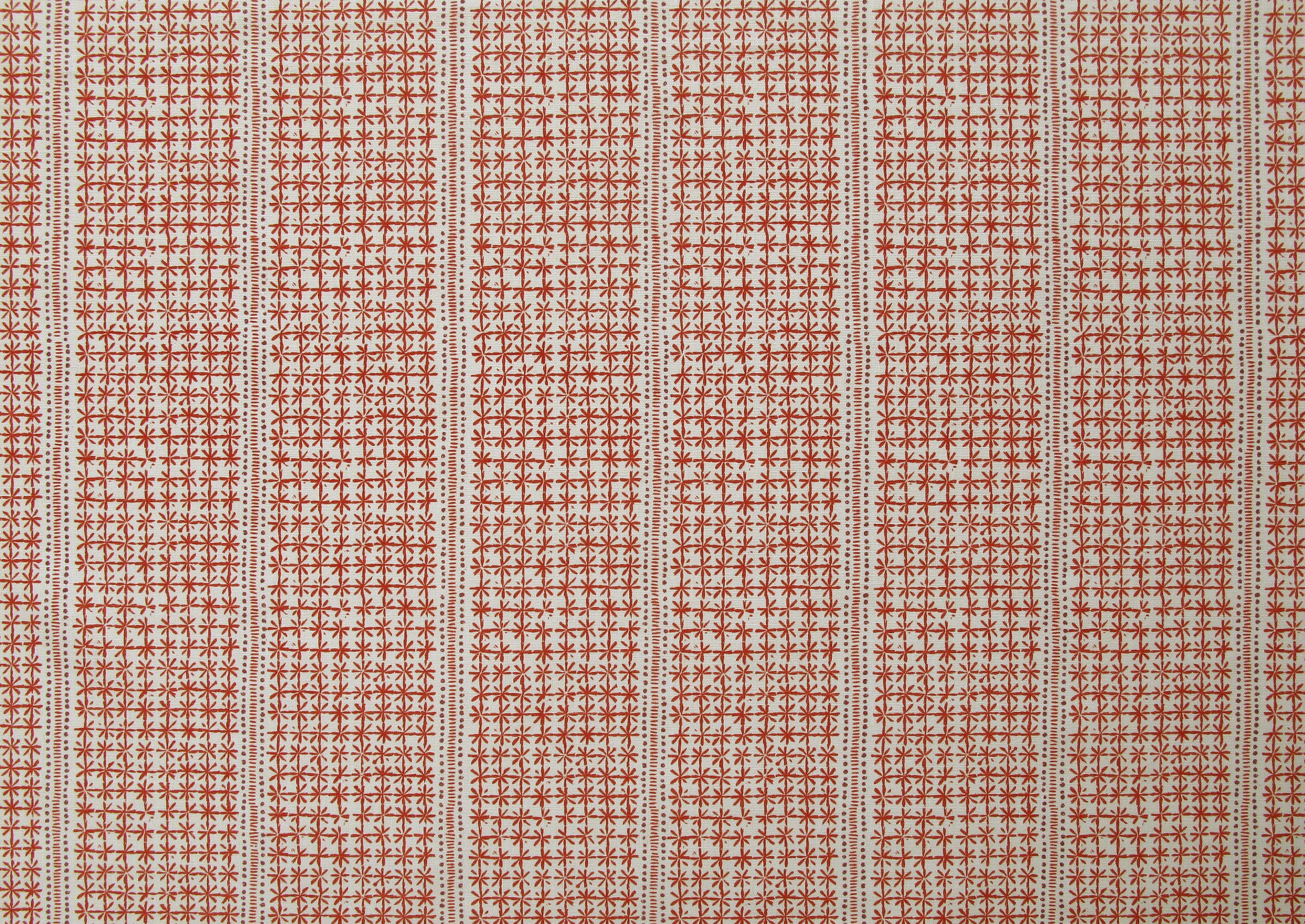 Detail of fabric in a dense repeating stripe and star print in red on a cream field.