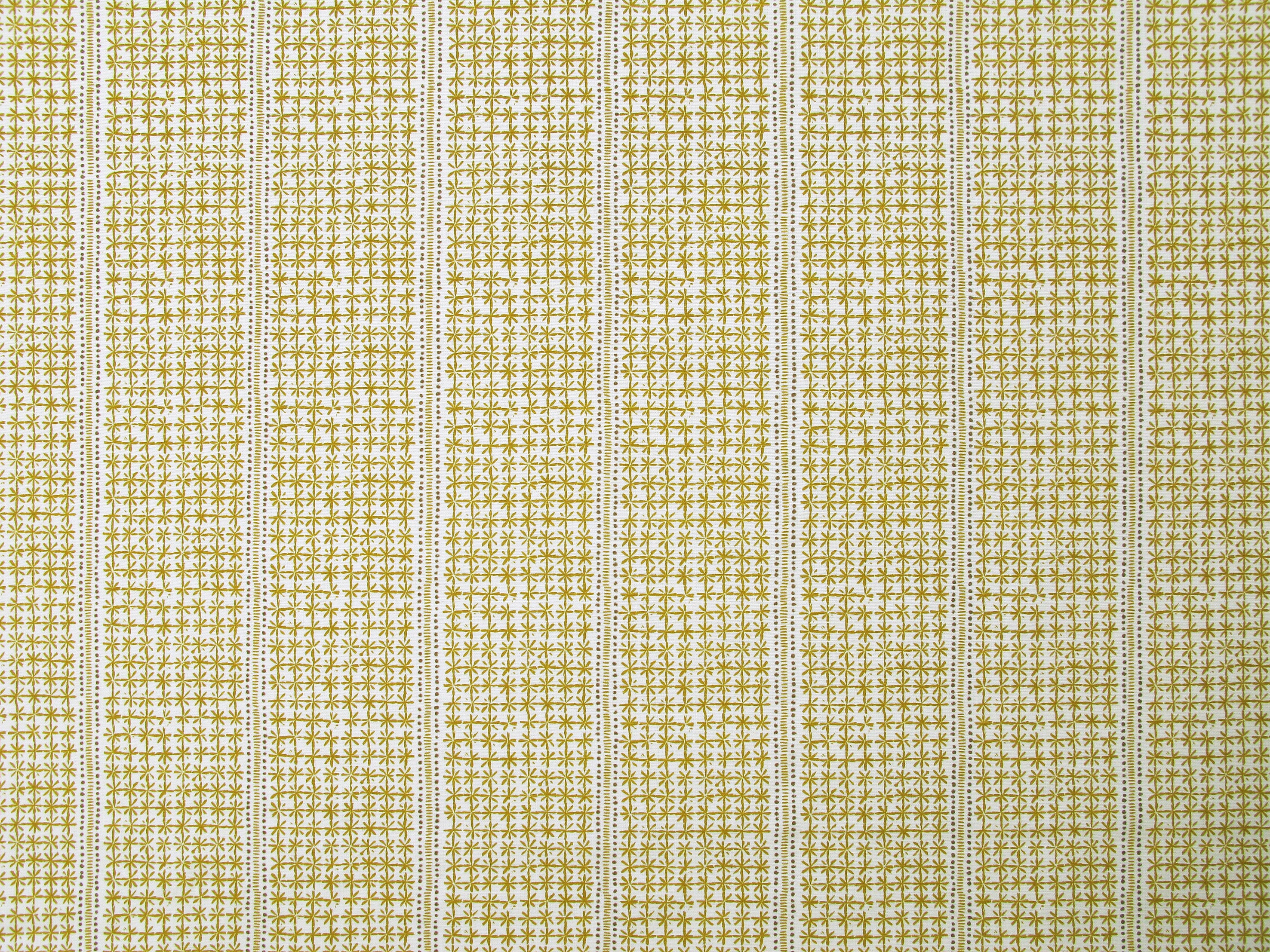 Detail of fabric in a dense repeating stripe and star print in mustard on a cream field.