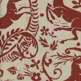 Close-up of fabric in a deer, leaf and flower print in red on a tan field.