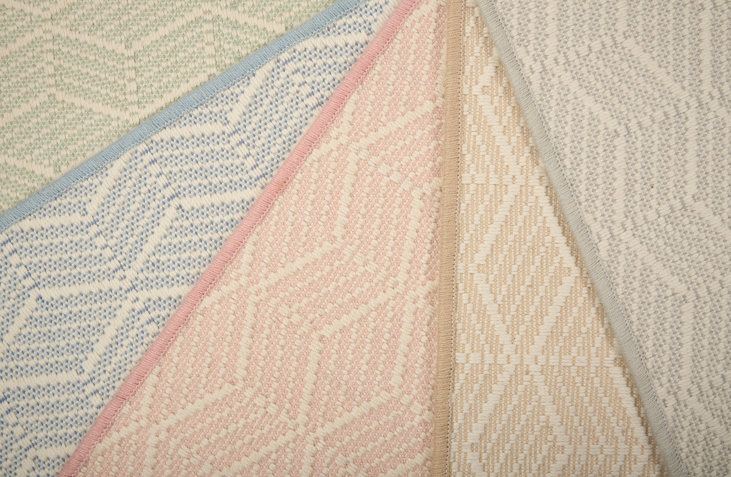 Stack of broadloom carpets in a dimensional herringbone stripe pattern in an array of pastel colors. 