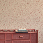 Woven red sideboard against a hand drawn floral patterned beige wall