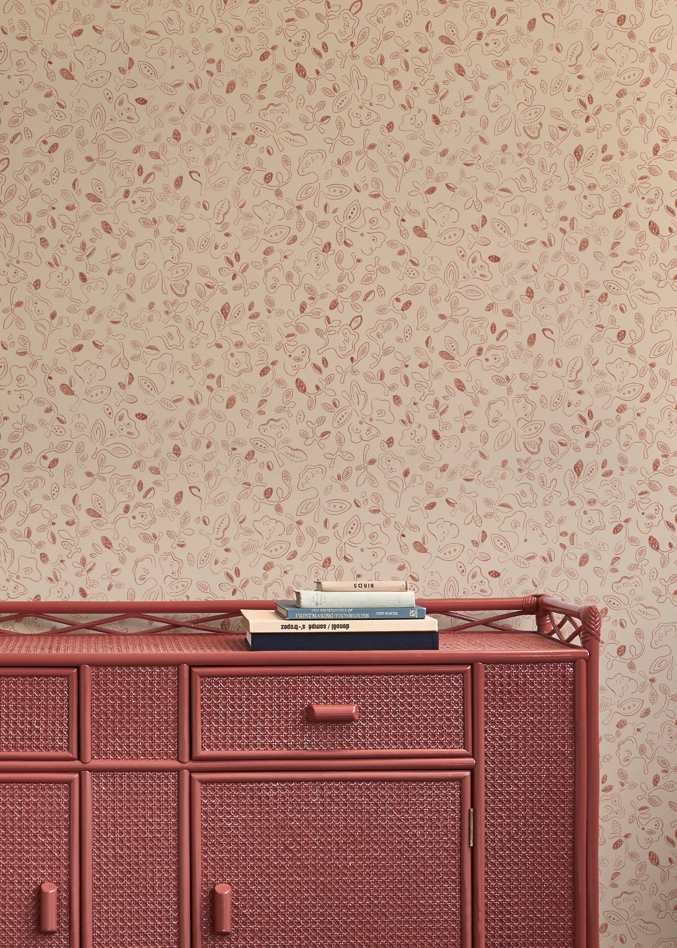 Woven red sideboard against a hand drawn floral patterned beige wall