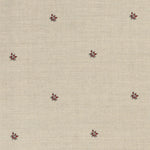 Detail of a printed linen fabric in a repeating small-scale flower pattern in red and gray on a cream field.