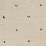 Detail of a printed linen fabric in a repeating small-scale flower pattern in red and gray on a cream field.