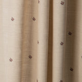 Draped printed linen fabric in a repeating small-scale flower pattern in red and gray on a cream field.