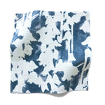 Square fabric swatch in a painterly bluebell pattern in white on a mottled navy field.