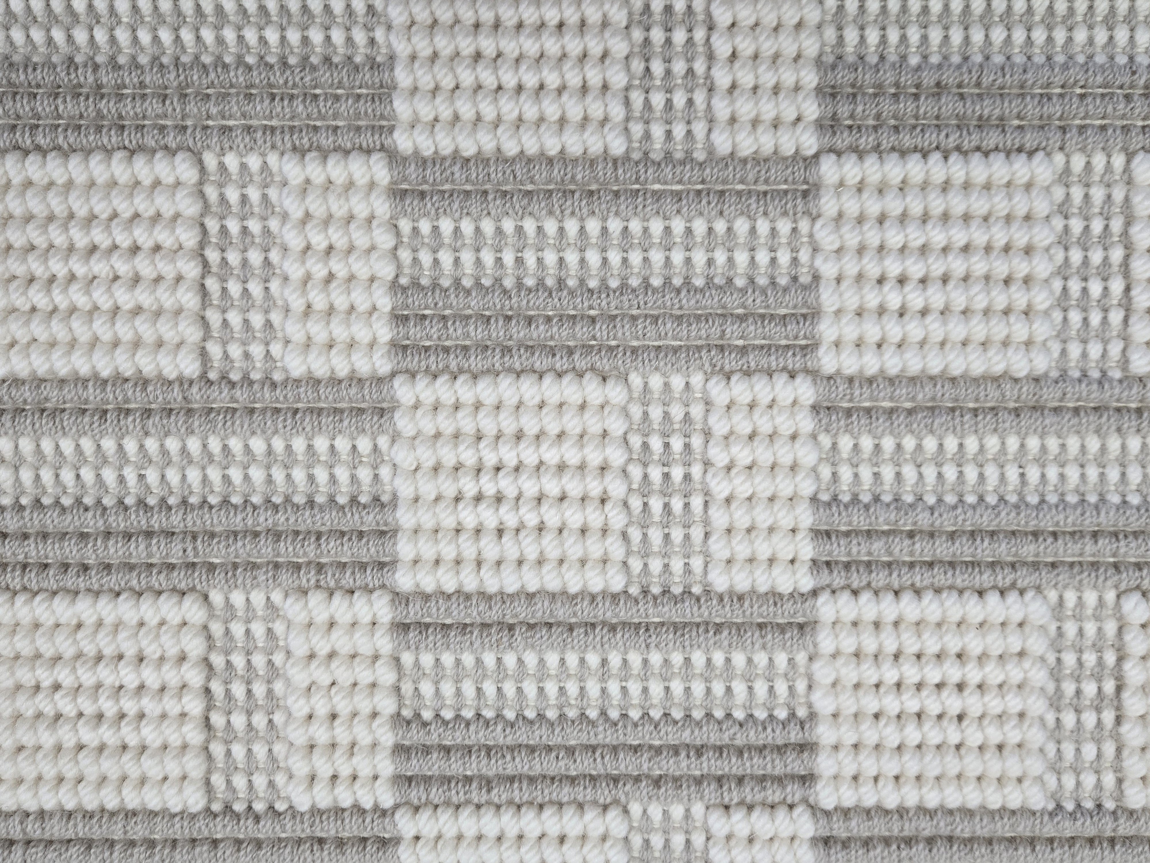 Broadloom carpet in a complex checkerboard pattern in ivory and cool grey.