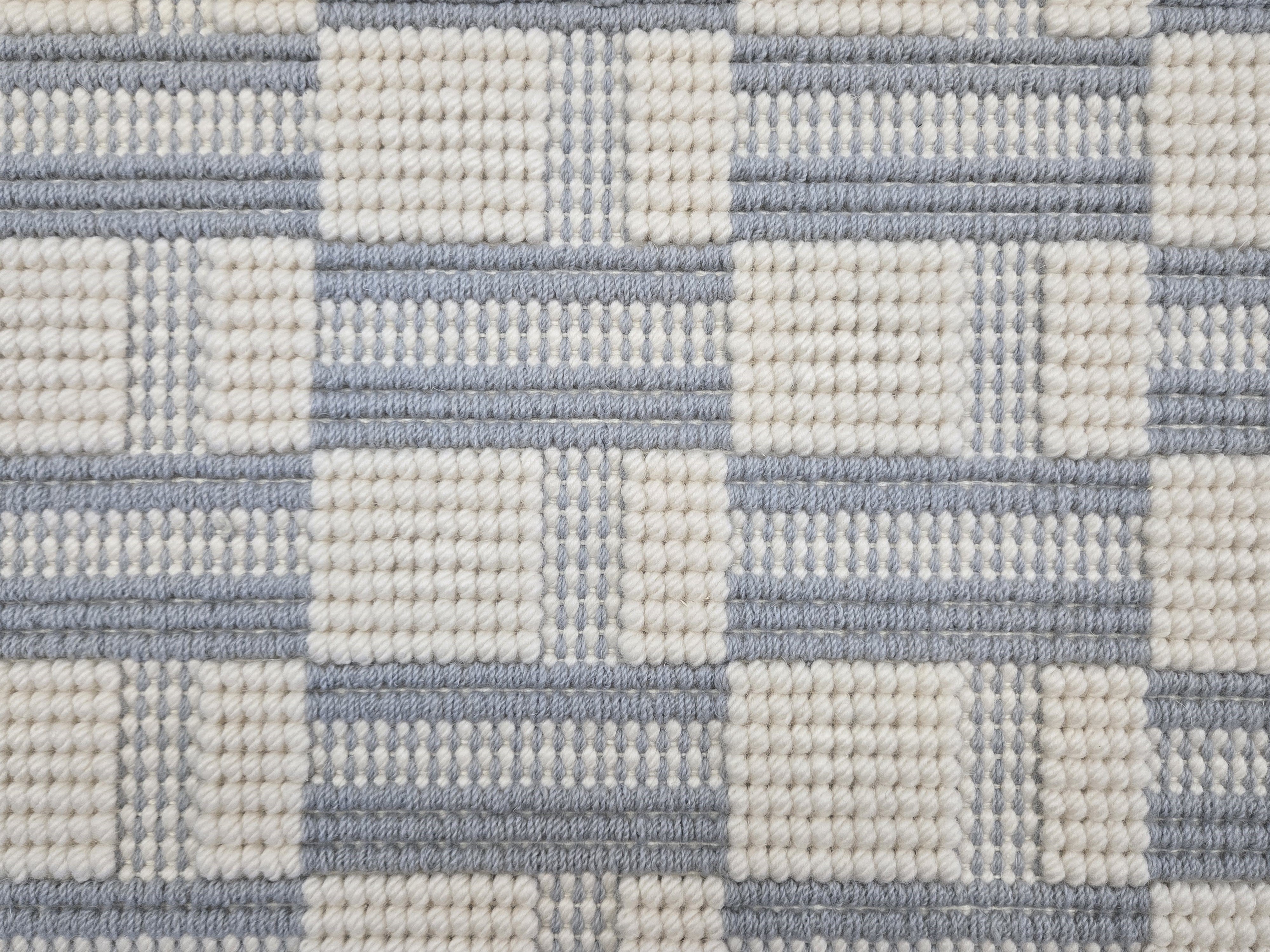 Broadloom carpet in a complex checkerboard pattern in ivory and light blue.