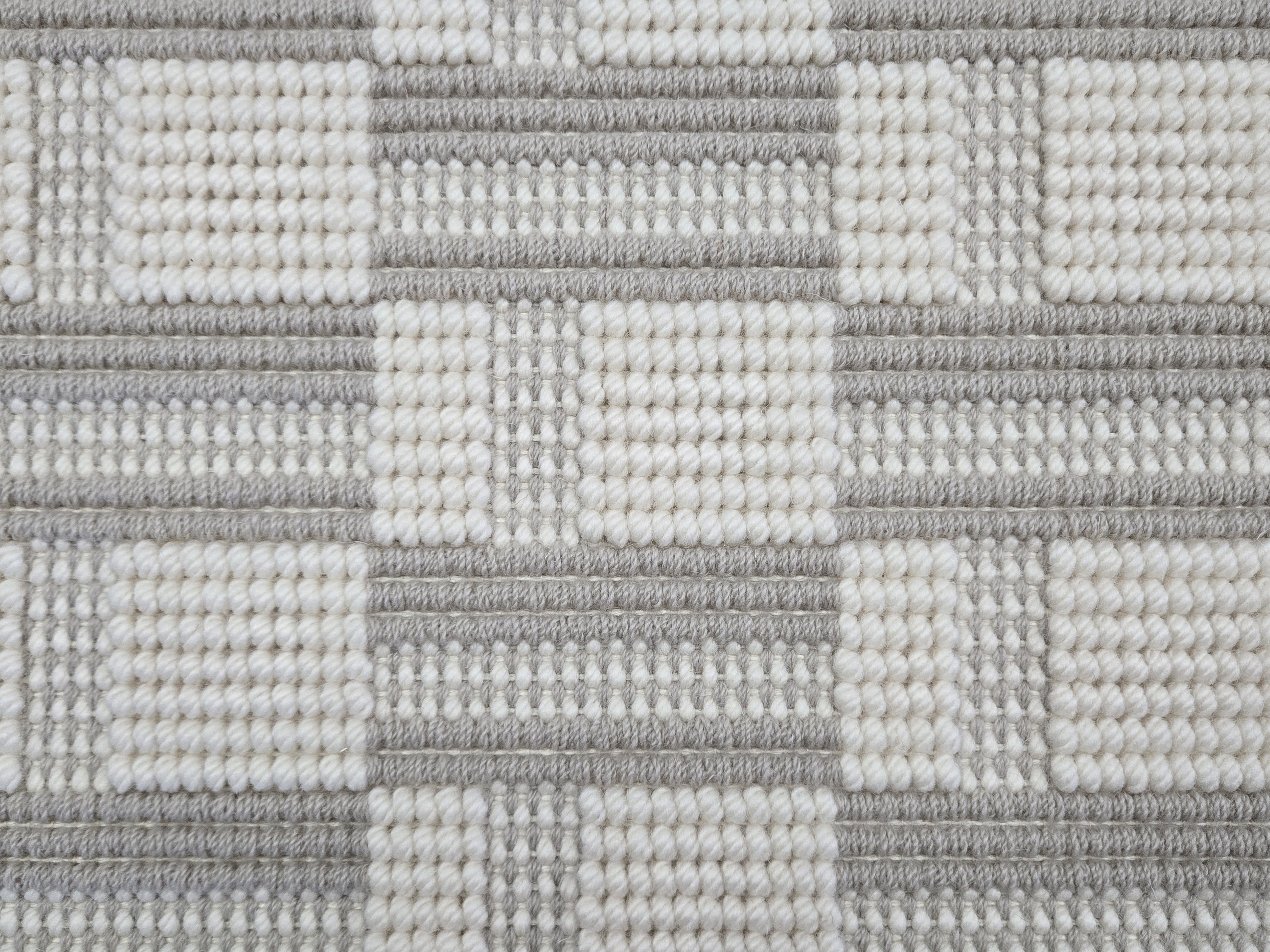 Broadloom carpet in a complex checkerboard pattern in ivory and light grey.