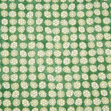 Detail of fabric in a circular floral print in light green and white on a mottled green field.