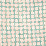 Detail of fabric in a circular floral print in light pink and white on a mottled turquoise field.