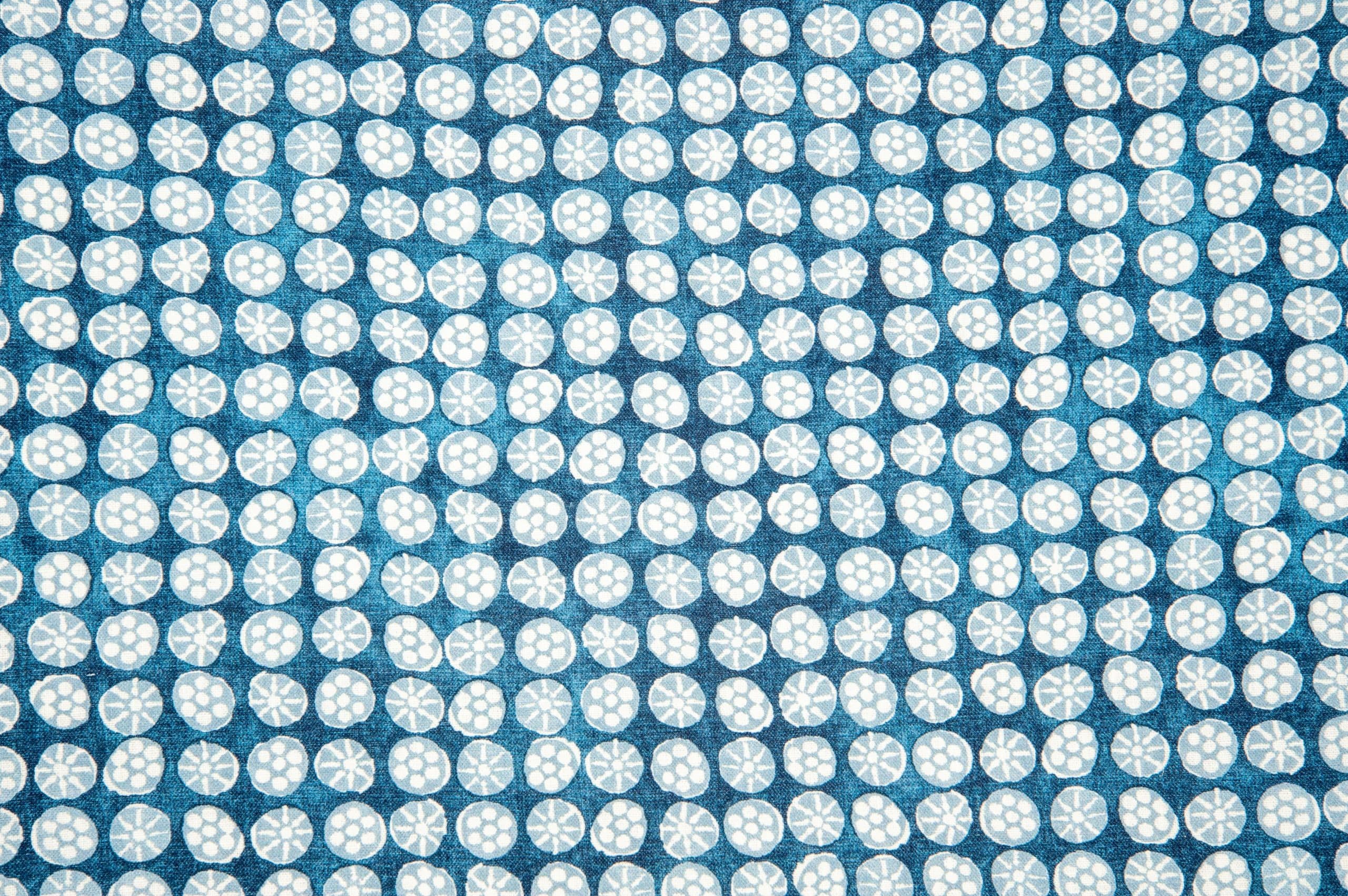 Detail of fabric in a circular floral print in light blue and white on a mottled blue field.