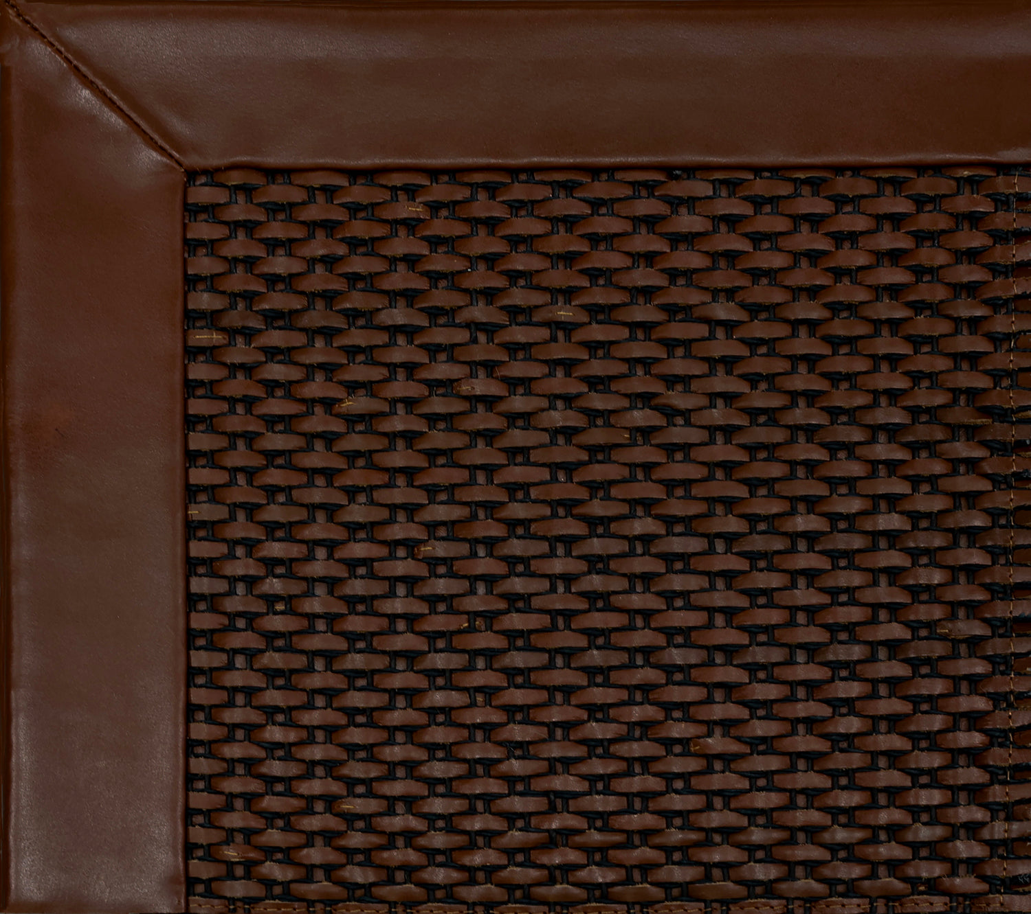 Close-up of woven leather rug with a wide leather binding in warm brown.