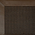 Close-up of a textured brown rug corner with a leather border