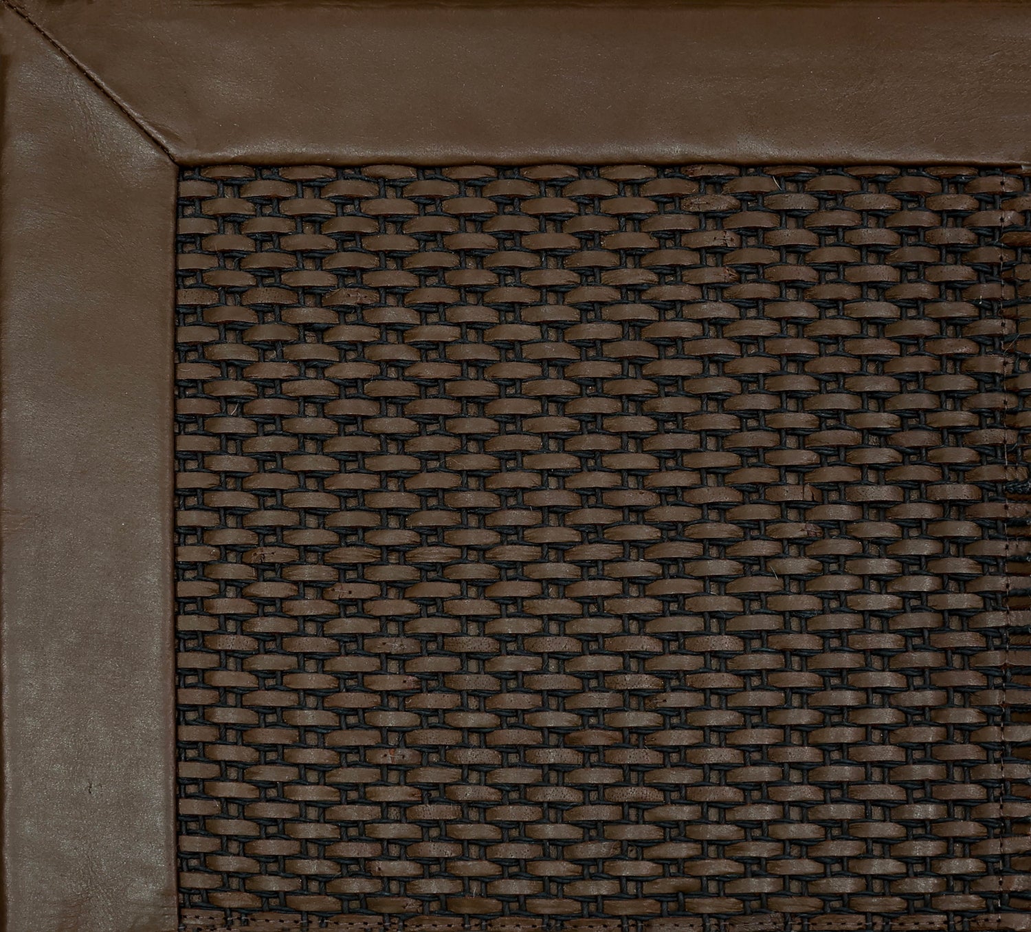 Close-up of a textured brown rug corner with a leather border