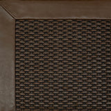 Close-up of a textured brown rug corner with a leather border
