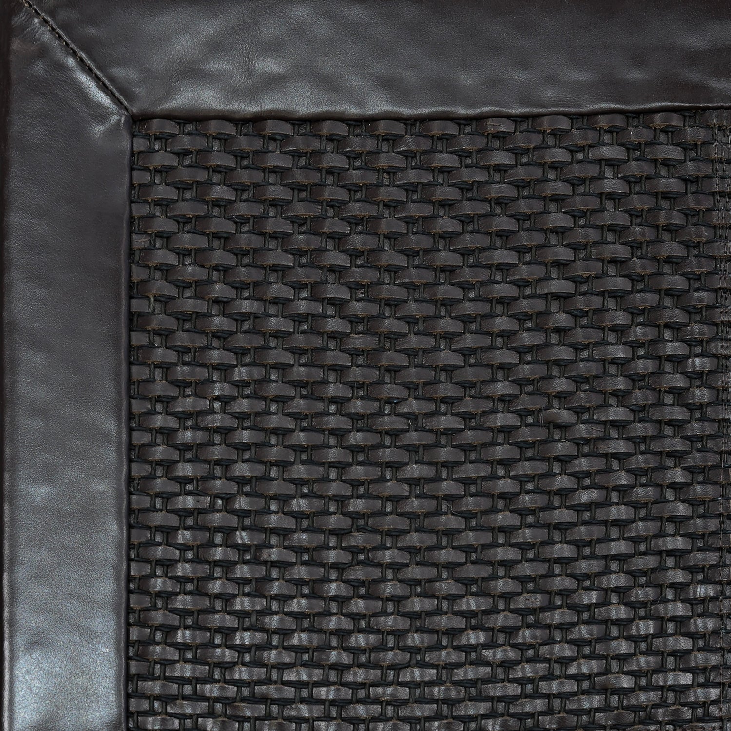 Close-up of woven leather rug with a wide leather binding in dark brown.