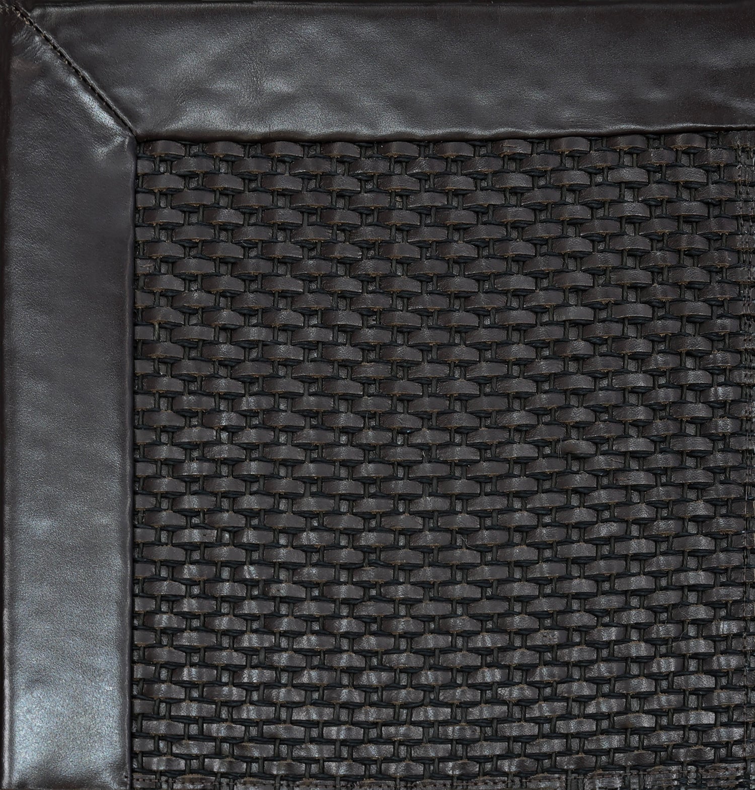 Close-up of woven leather rug with a wide leather binding in dark brown.