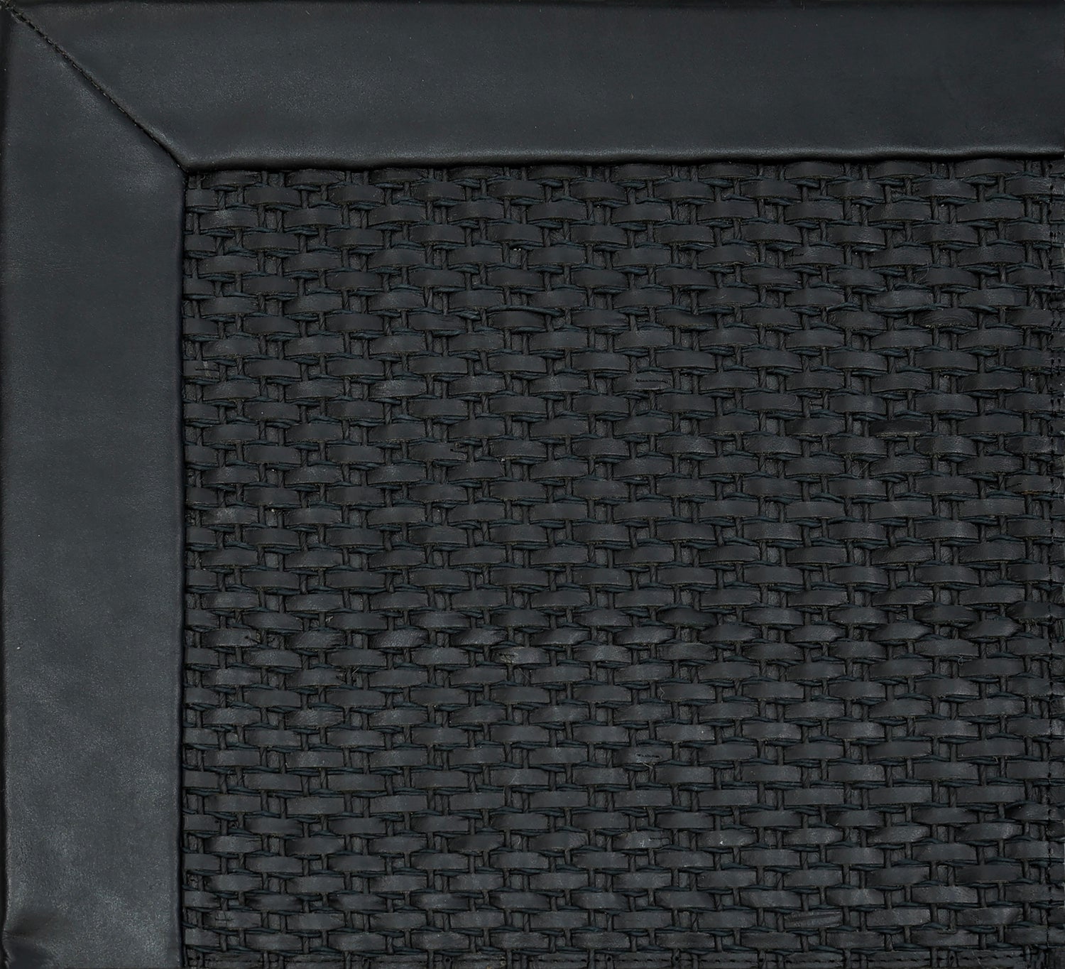 Close-up of woven leather rug with a wide leather binding in black.