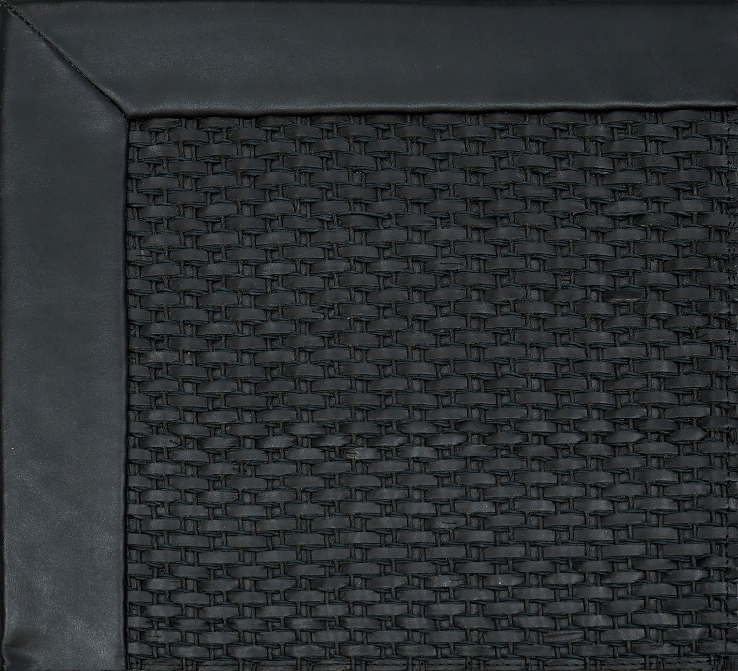 Close-up of woven leather rug with a wide leather binding in black.