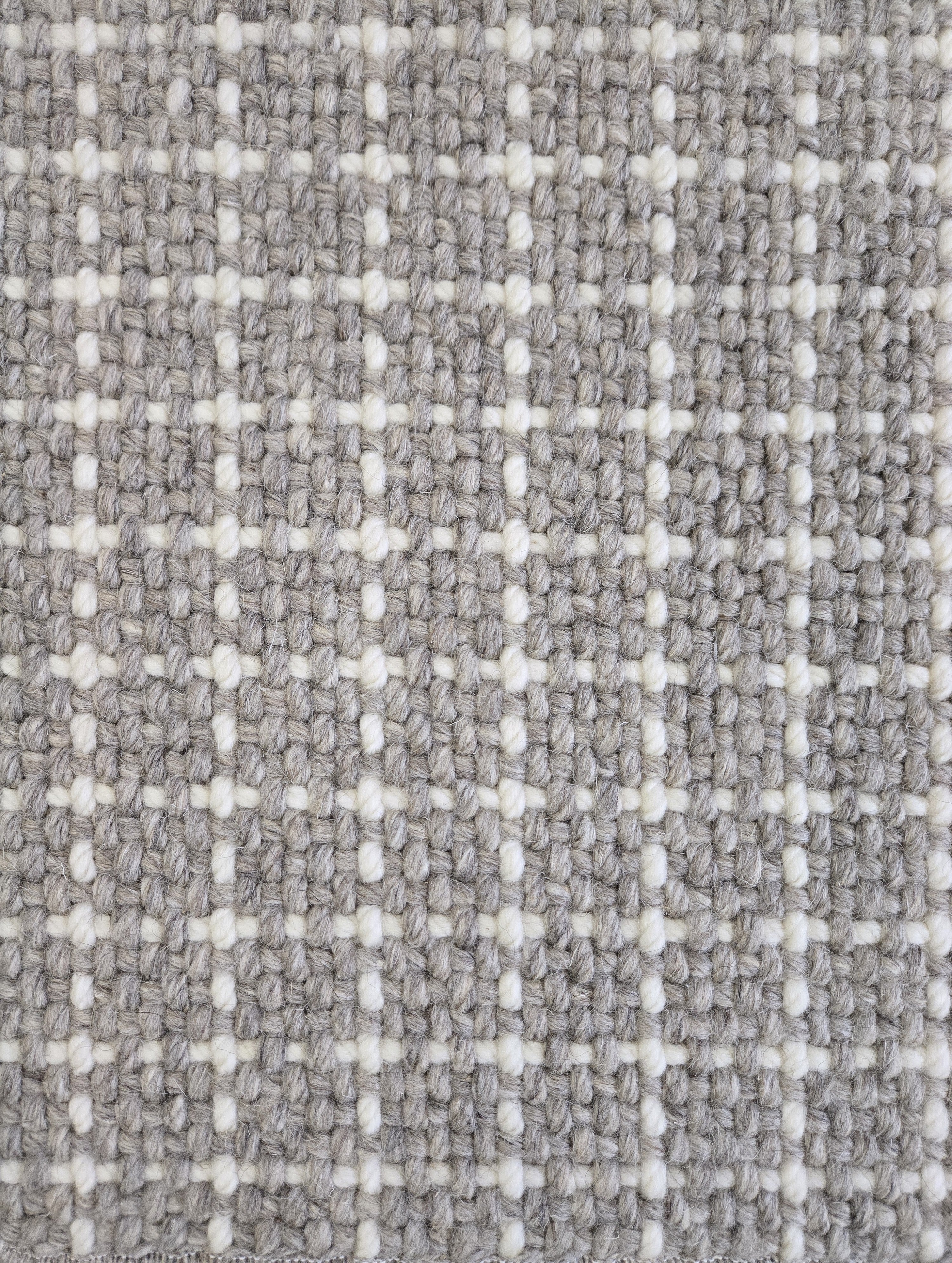Close-up of a carpet with a textured check pattern in grey and white.