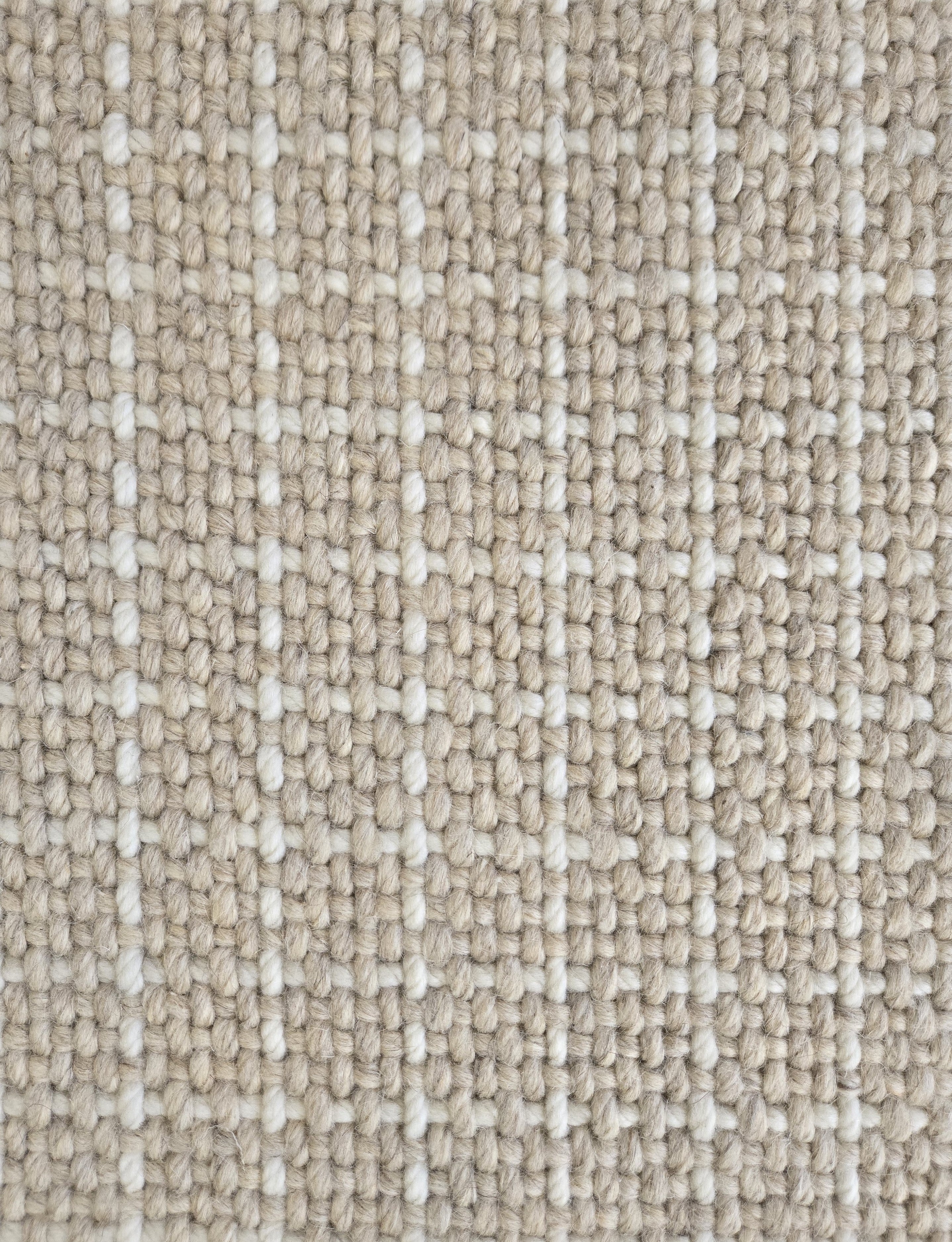Close-up of a carpet with a textured check pattern in beige and cream. 