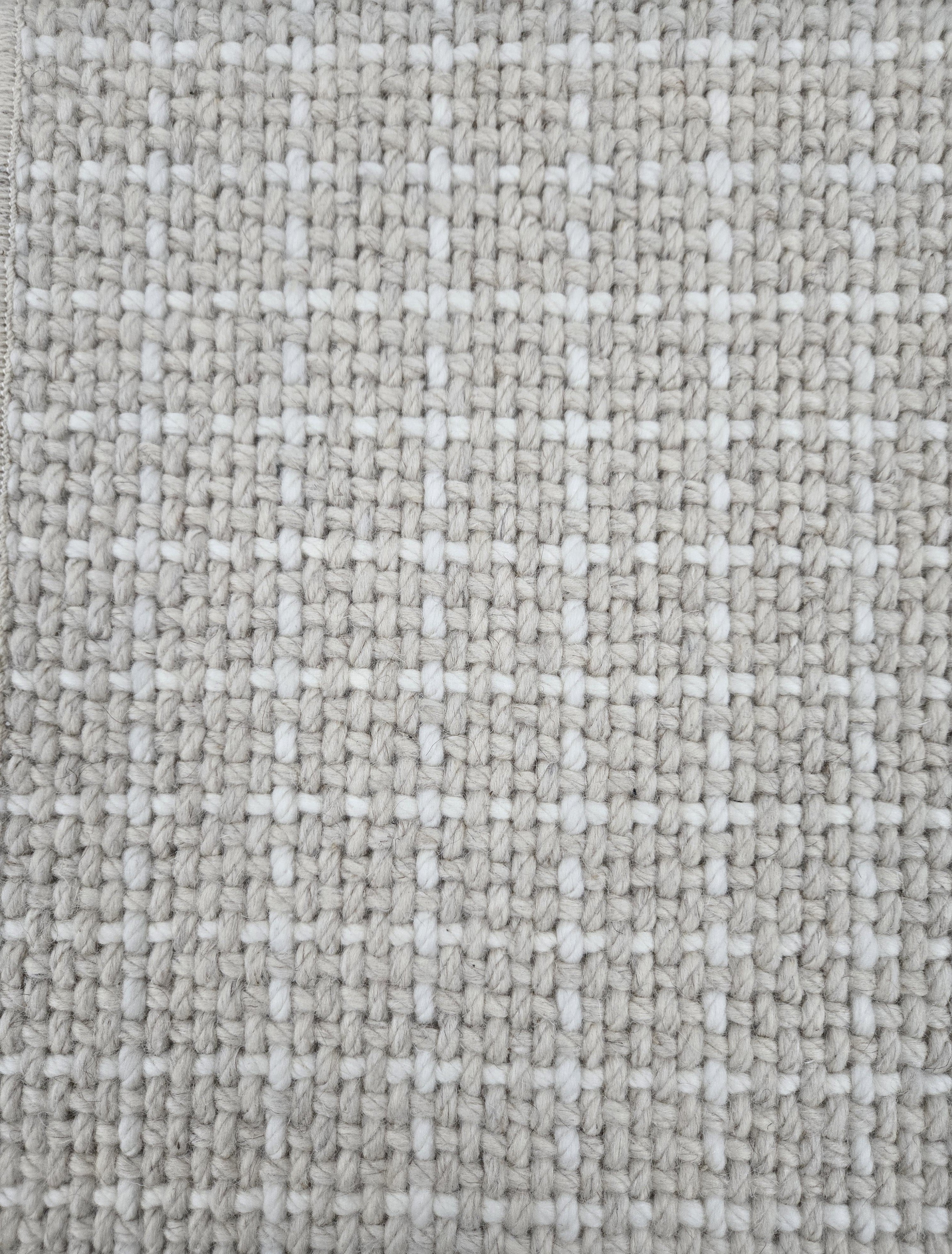 Close-up of a carpet with a textured check pattern in beige and white.