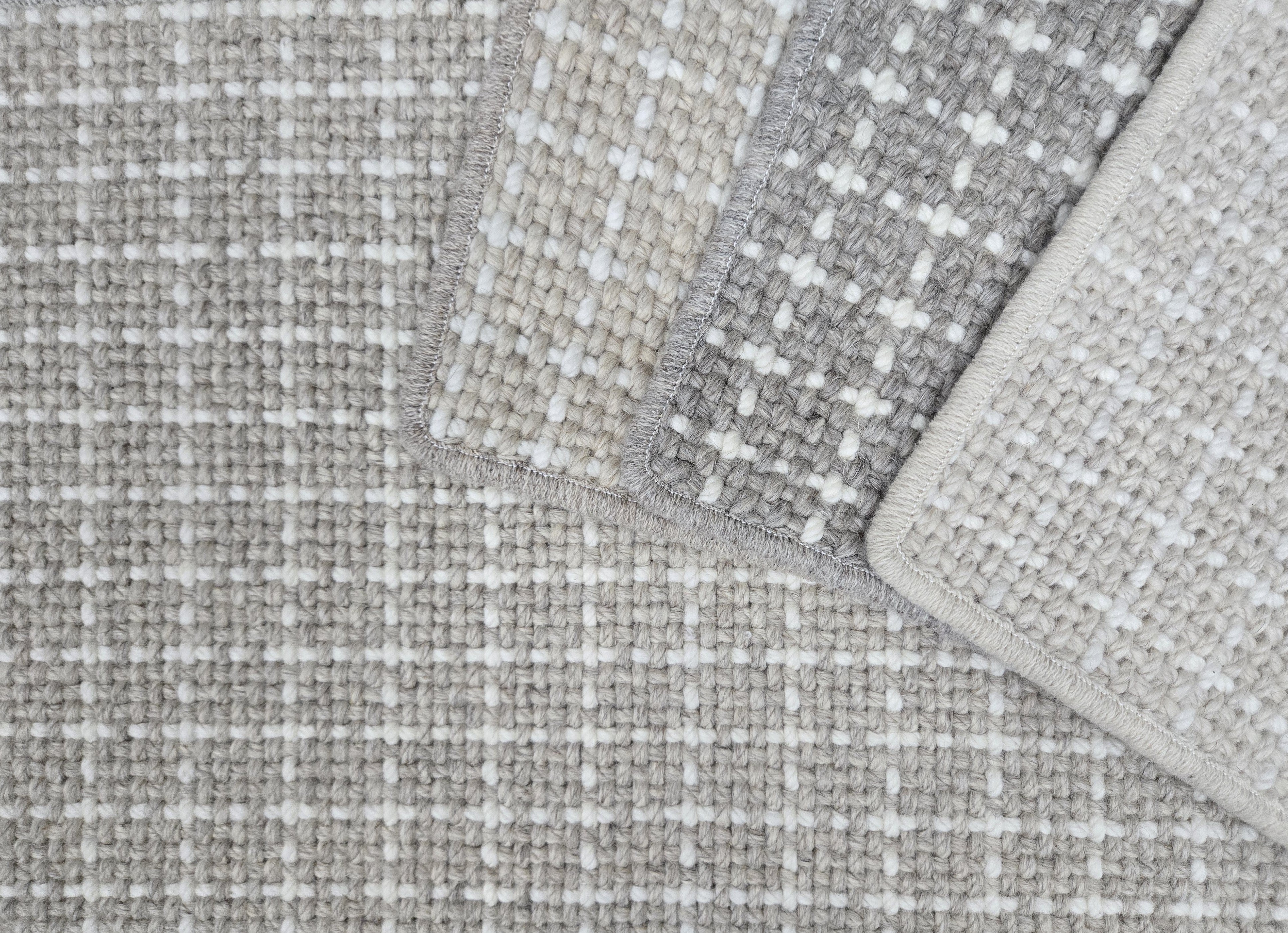 Close-up of check patterned carpet samples in neutral colors. 