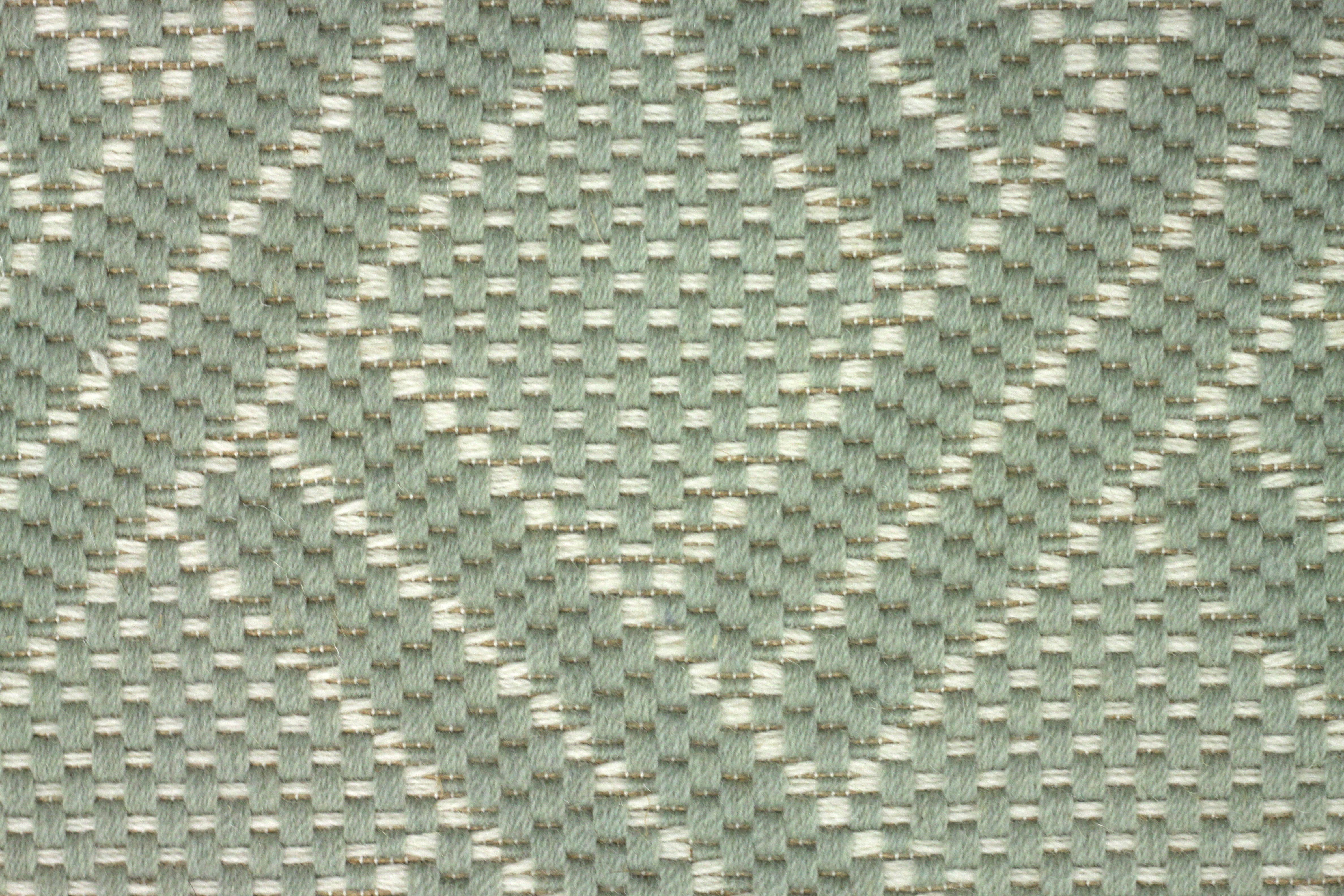 Broadloom carpet in a diamond lattice pattern in light green and cream. 