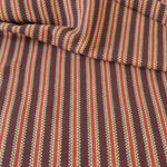 Detail of a draped hand-woven cotton striped fabric in shades of red, brown and yellow.