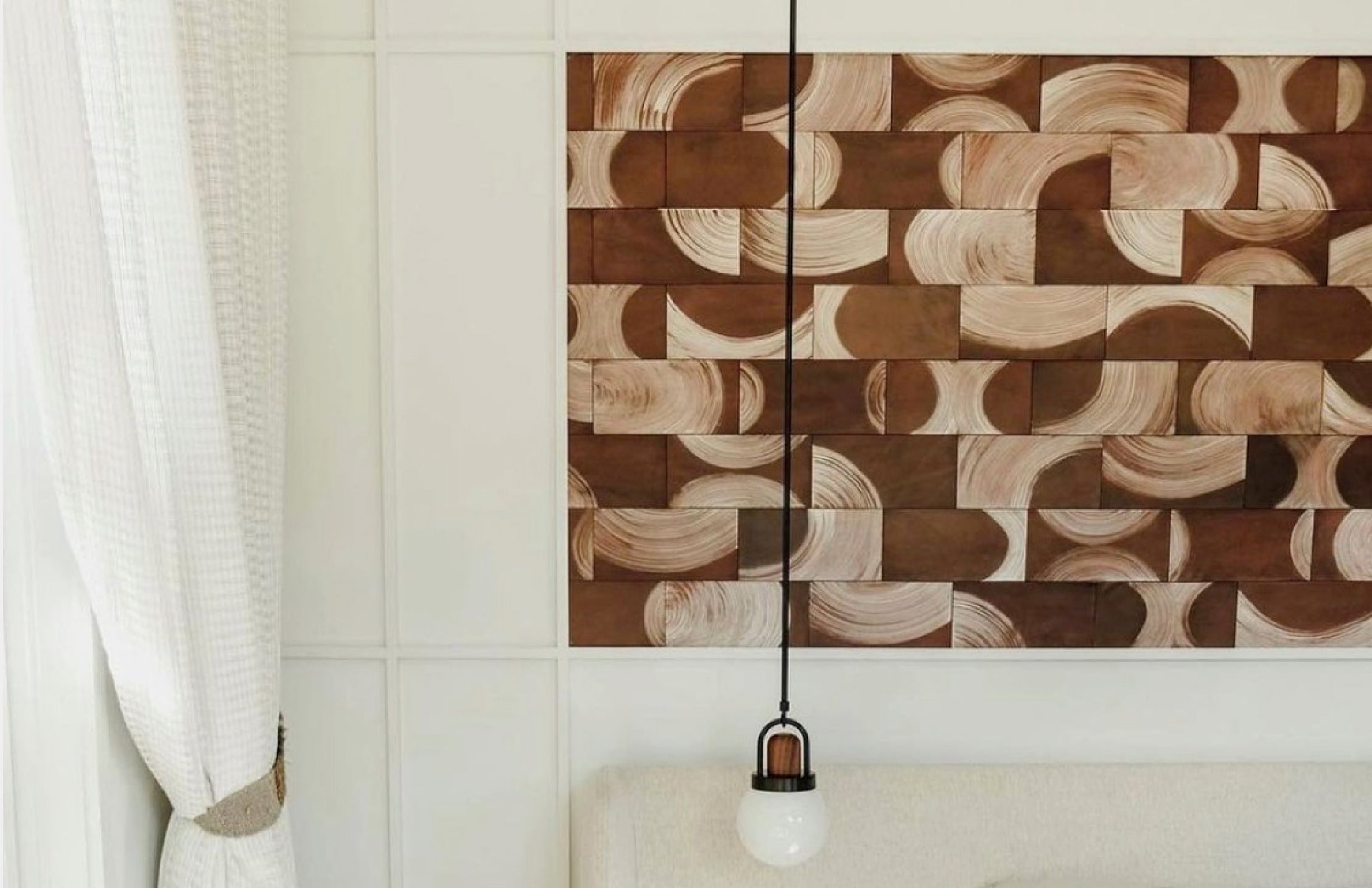 An inlaid panel over a headboard of leather wall tiles in a repeating curvolinear pattern in brown and tan.