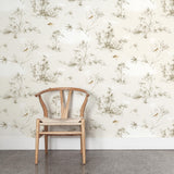 A wooden chair stands in front of a wall papered in a painterly bird and branch print in shades of brown, white and cream.