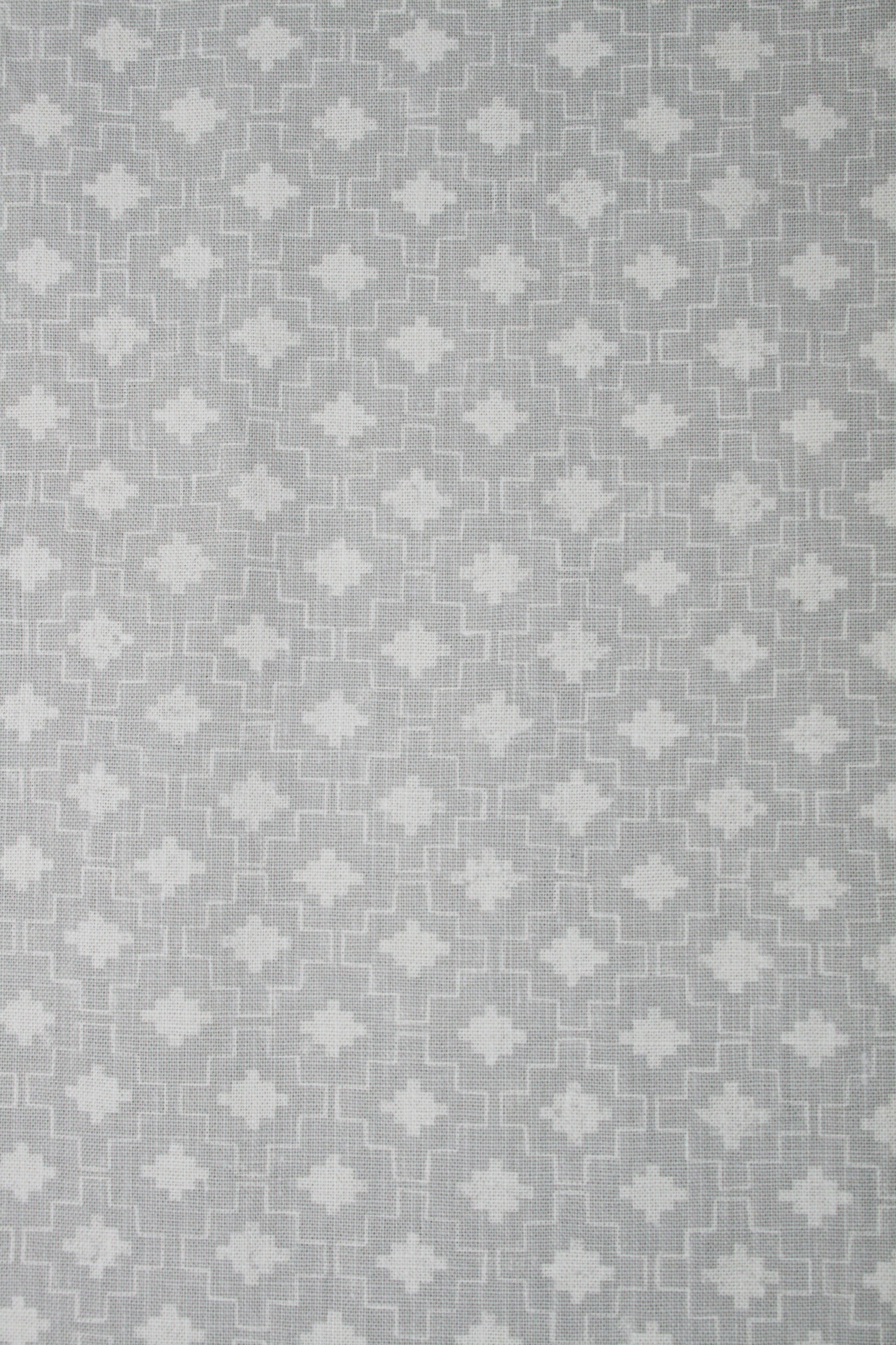 Detail of fabric in a geometric grid print in white on a gray field.