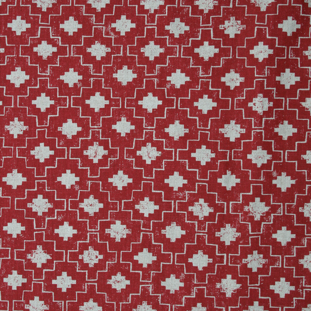 Detail of fabric in a geometric grid print in white on a red field.