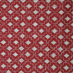 Detail of fabric in a geometric grid print in white on a red field.