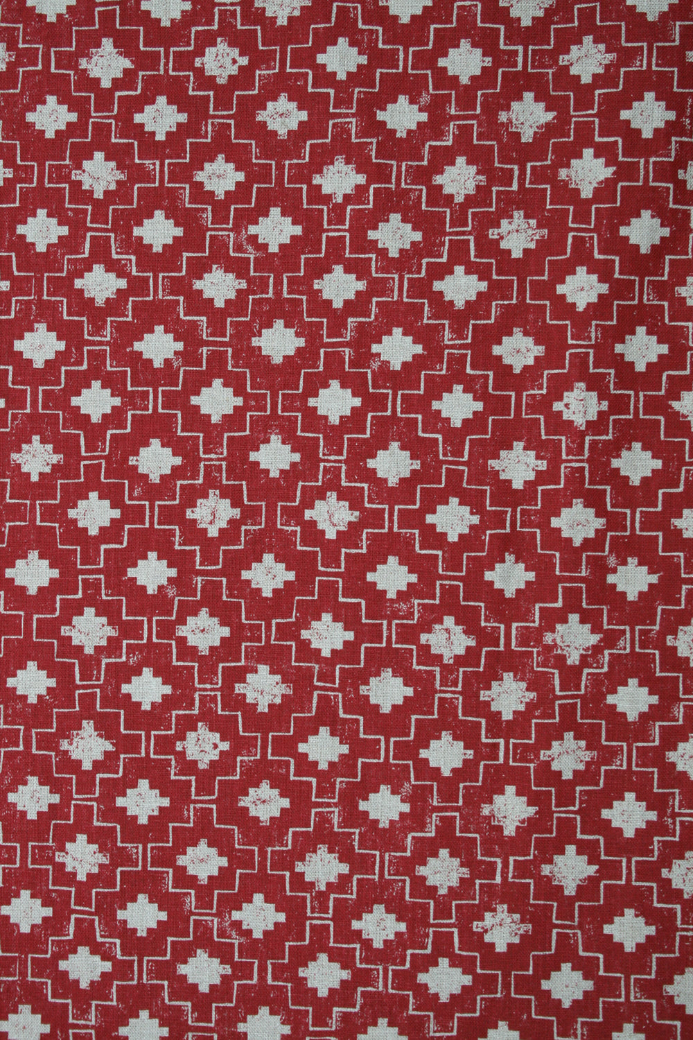 Detail of fabric in a geometric grid print in white on a red field.