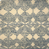 Handknotted rug with dotted geometric motif in blue on a cream field. 
