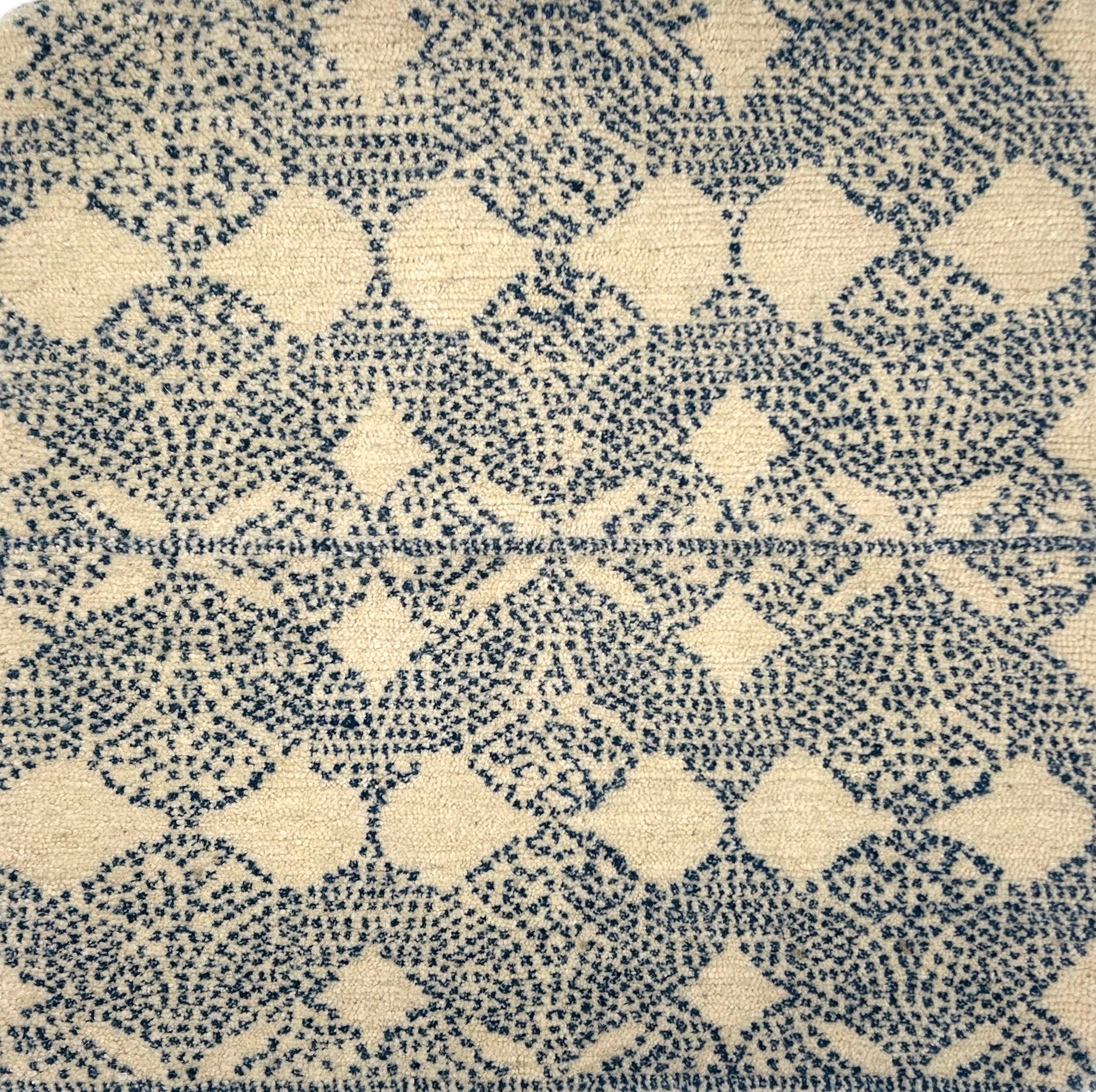 Handknotted rug with dotted geometric motif in blue on a cream field. 