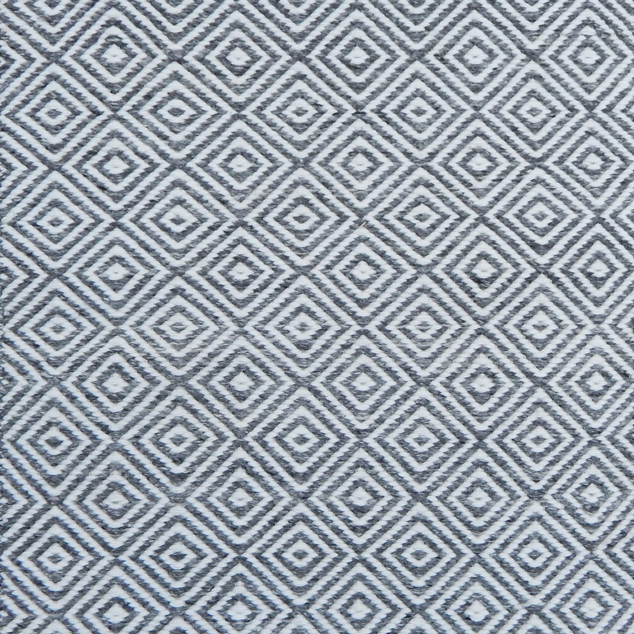 Patterned rug with a geometric diamond design in grey and white.