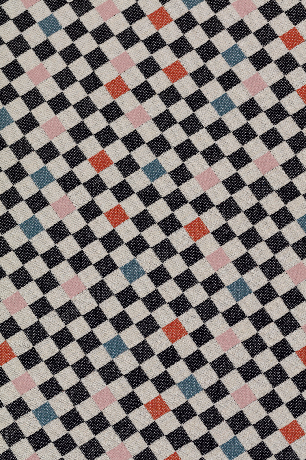 Detail of jacquard fabric in a checked pattern in shades of pink, red, blue and black on a tan field.