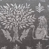 Close-up of fabric in a lion and plant print in white on a mottled gray field.