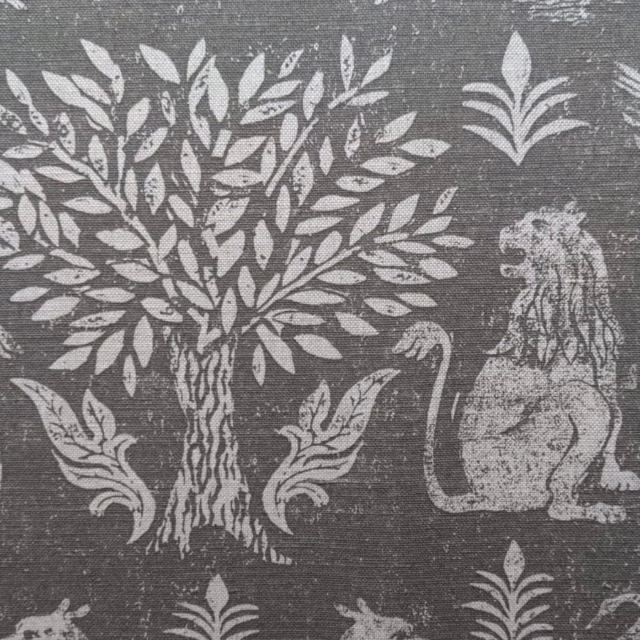 Close-up of fabric in a lion and plant print in white on a mottled gray field.