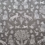 Detail of fabric in a lion and plant print in white on a mottled gray field.