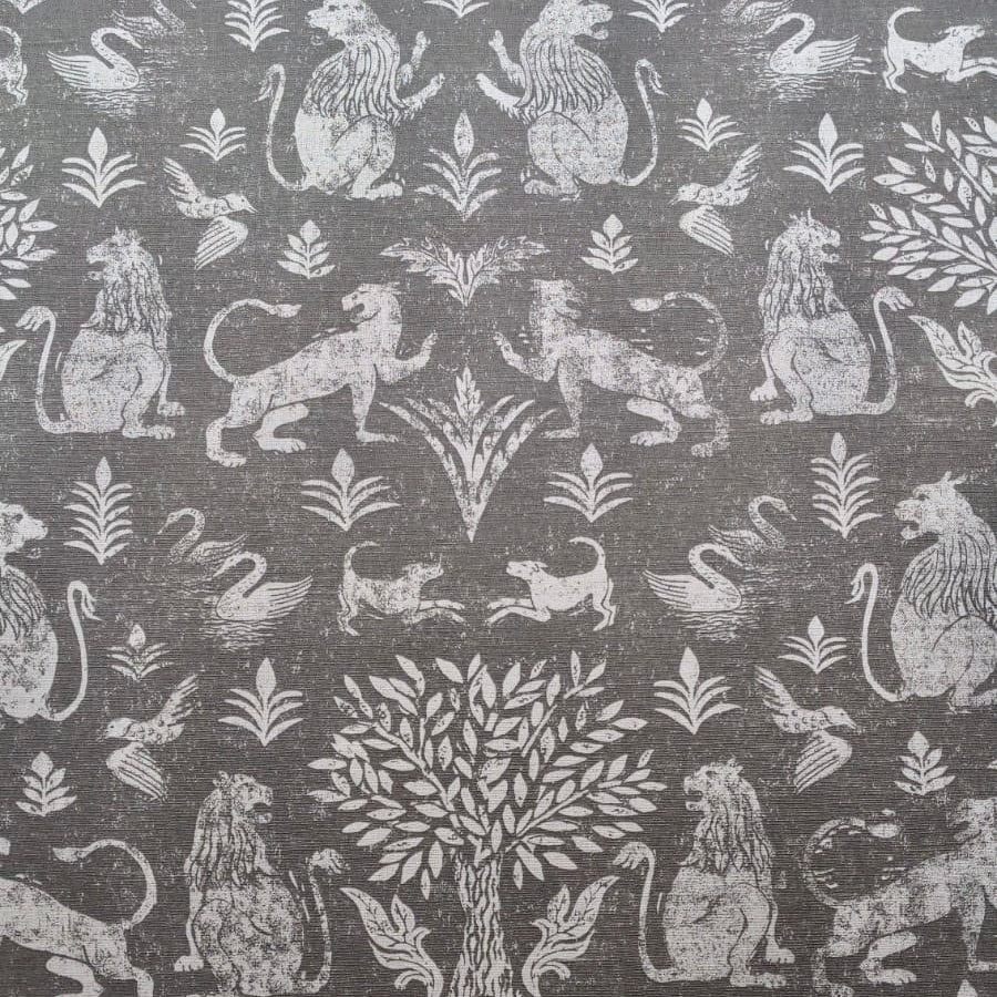 Detail of fabric in a lion and plant print in white on a mottled gray field.